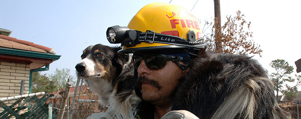 FEMA Urban Search and Rescue Task Force member carries his dog over an area that is muddy in an area impacted by Hurricane Katrina